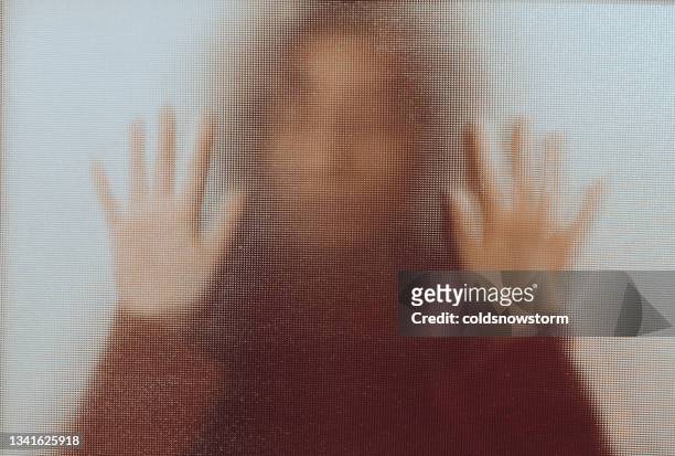domestic abuse victim with hands pressed against glass window - violence stock pictures, royalty-free photos & images