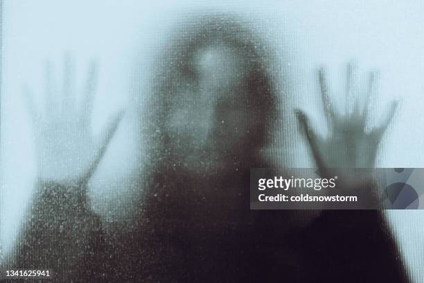 domestic abuse victim with hands pressed against glass window - espectro imagens e fotografias de stock