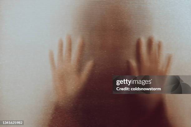 domestic abuse victim with hands pressed against glass window - human trafficking stock pictures, royalty-free photos & images