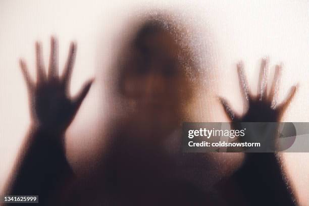 domestic abuse victim with hands pressed against glass window - terrorismo imagens e fotografias de stock