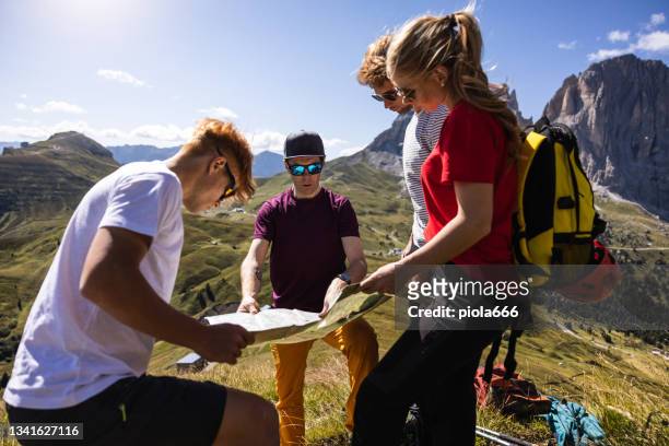 alpiner bergführer zeigt der familienwandergruppe wanderwege auf der karte - gardena stock-fotos und bilder
