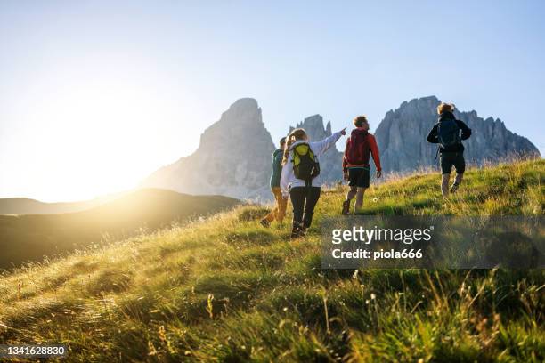 gruppe von freunden wandern auf dem berg bei sonnenuntergang - anführen stock-fotos und bilder