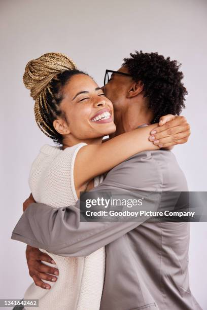 laughing young woman hugging her boyfriend against a white background - arm around stock pictures, royalty-free photos & images