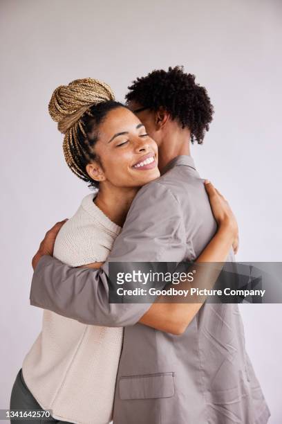 smiling young woman hugging her boyfriend against a white background - couple studio stock pictures, royalty-free photos & images