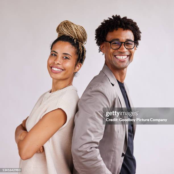 smiling young businesspeople standing back to back against a white background - two people portrait stock pictures, royalty-free photos & images