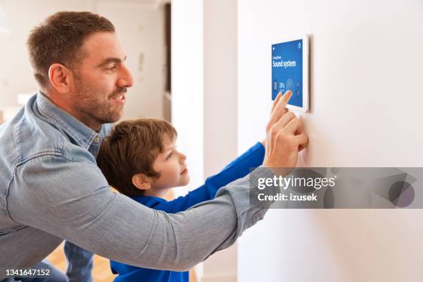 padre con figlio che controlla i dispositivi intelligenti con un tablet digitale a casa - termostato foto e immagini stock