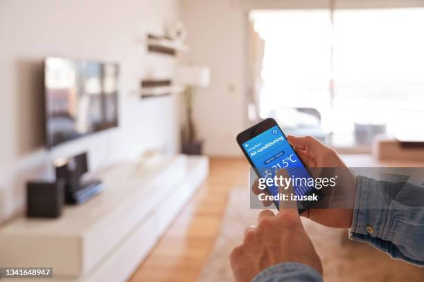 man controlling smart devices using phonet at home - burglar alarm stock pictures, royalty-free photos & images