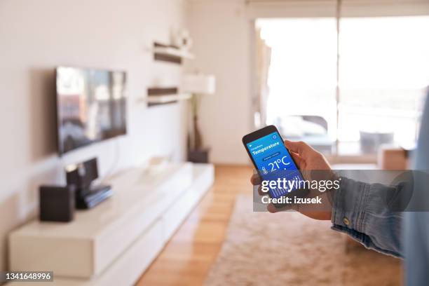 man controlling smart devices using phonet at home - telephone switch stockfoto's en -beelden