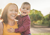 Happy latin mother holding son in her arms and laughing on camera - Mother and child love