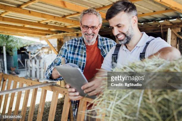 father and son farmers planning their production and using tablet - village life stockfoto's en -beelden