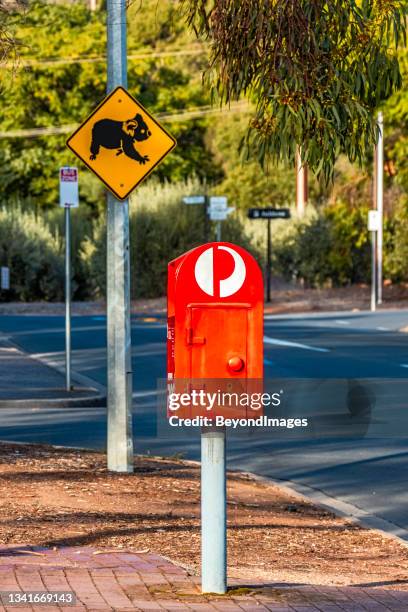 australia post red street posting box with yellow koala crossing sign and bushland foliage - green and red autumn leaves australia stock pictures, royalty-free photos & images