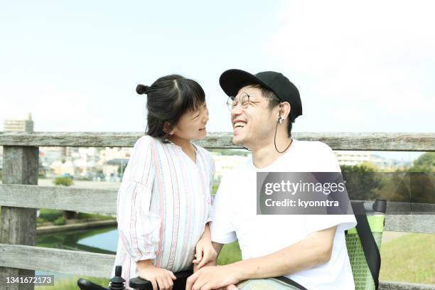 asian father wheelchair user smiles with his daughter - amyotrophic lateral sclerosis stock pictures, royalty-free photos & images