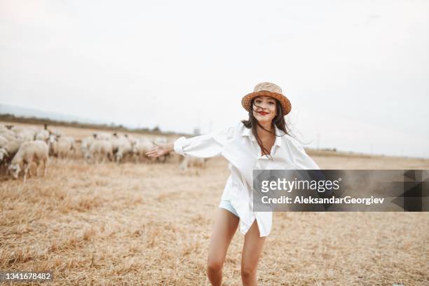 bellezza femminile eccitata che corre di fronte alle pecore sui campi di fieno - paglia foto e immagini stock