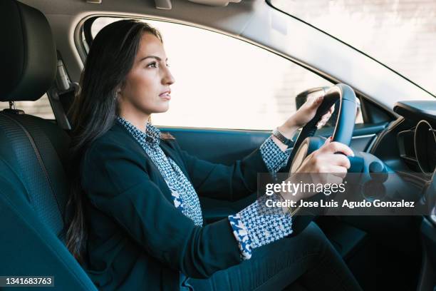 young hispanic woman drives a modern vehicle - female driving stock pictures, royalty-free photos & images