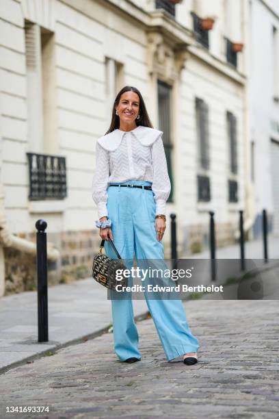 Alba Garavito Torre wears pearls earrings, a white lace collar long puffy sleeves shirt with embroidered polka dots, a small black shiny leather...