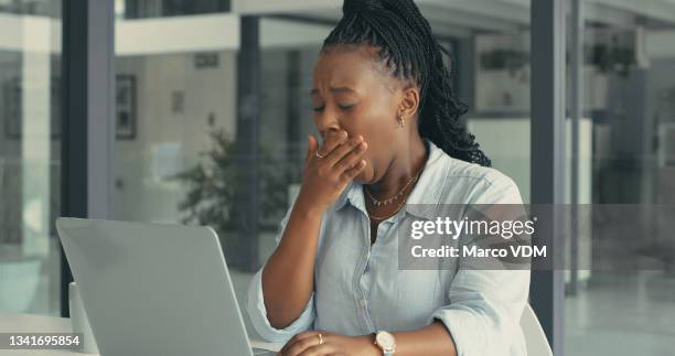 shot of a beautiful young woman looking exhausted while working in a modern office - yawn office stockfoto's en -beelden