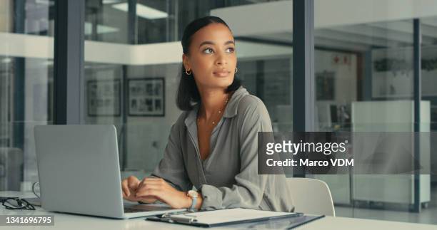 shot of a beautiful young woman lost in thought while using her laptop in a modern office - business woman sitting imagens e fotografias de stock