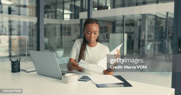 aufnahme einer schönen jungen frau, die in einem modernen büro papierkram erledigt - black man laptop stock-fotos und bilder