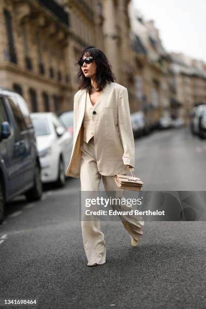 Fashion blogger Xiayan wears black sunglasses, a silver large chain necklace, a beige buttoned V-neck short sleeves jacket as a t-shirt, a matching...