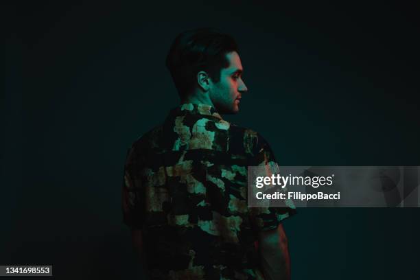 rear view of a young adult man with colorful lights in studio - 80s male model stock pictures, royalty-free photos & images