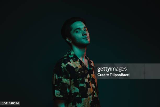 portrait in studio with colorful lights of a young adult man - gel effect lighting 個照片及圖片檔