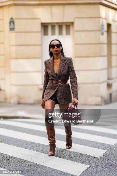 Emilie Joseph @in_fashionwetrust wears silver and gold earrings, a brown prince of Wales checked wool structured blazer cinched with a brown leather...