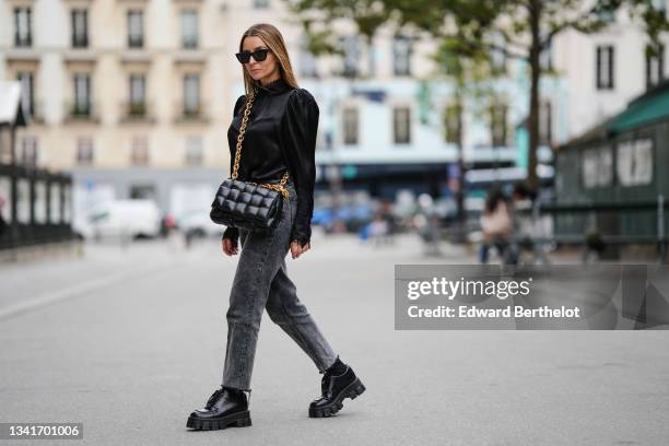 Julia Comil wears black cat eye sunglasses by Saint Laurent, a black silk blouse with puffed shoulders by Frame, a black shiny leather padded...
