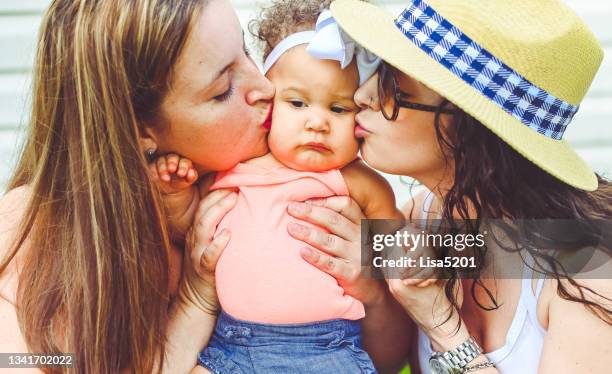 lesbian couple kiss their mixed race baby girl on either cheek in cute quirky portrait - photos of lesbians kissing stock pictures, royalty-free photos & images