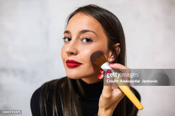 a beautiful young woman applying a blush with a big brush - blusher make up stock pictures, royalty-free photos & images