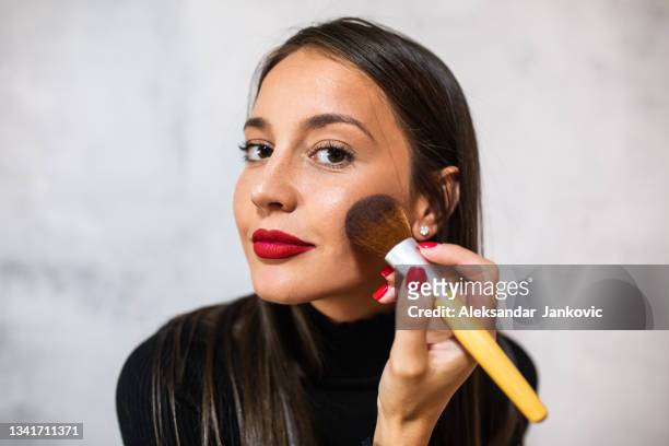a beautiful young woman applying a blush with a big brush - make up blush imagens e fotografias de stock