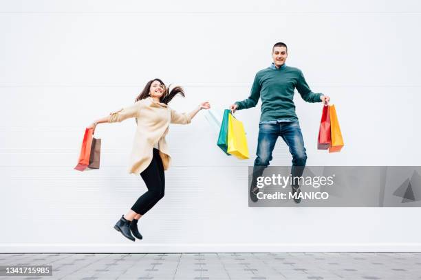 woman and man jumping with shopping bags - shopping bags white background stock pictures, royalty-free photos & images