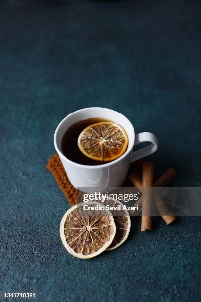 black tea with dried orange slices in a white mug on a dark turquoise green rough concrete floor - cinnamon stock pictures, royalty-free photos & images