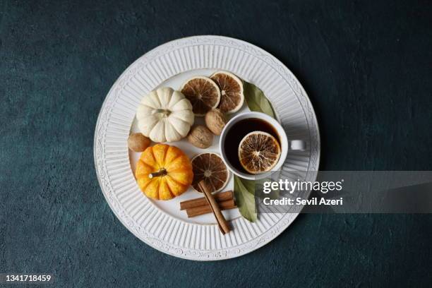 small white and orange pumpkins on a white wooden tray and black tea in a white mug. next to it are walnuts, cinnamon sticks and dried orange slices, autumn table decor - flat lay stock pictures, royalty-free photos & images