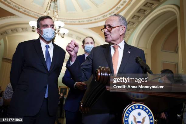 Sen. Mark Warner and Sen. Ron Wyden listen as Senate Majority Leader Chuck Schumer addresses reporters following a weekly Democratic policy meeting...