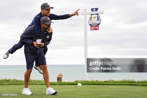 Justin Thomas of Team United States points toward the green as he jumps on the back of Michael Greller, caddie for Jordan Spieth of Team United...