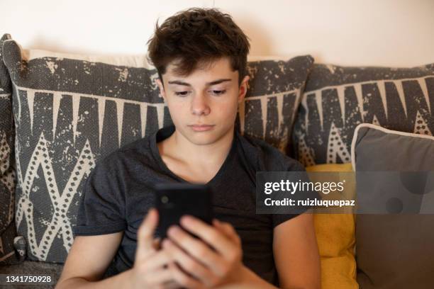 latin american teenager boy with smart phone at living room - only teenage boys stock pictures, royalty-free photos & images