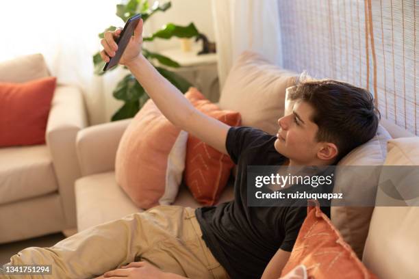 latin american teenager boy with smart phone at living room - only teenage boys stock pictures, royalty-free photos & images