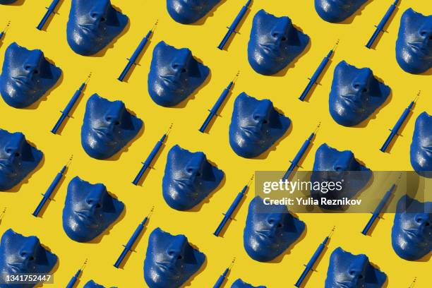 repeated blue colored syringe and face/ mask on the yellow background. - schönheitsoperation stock-fotos und bilder