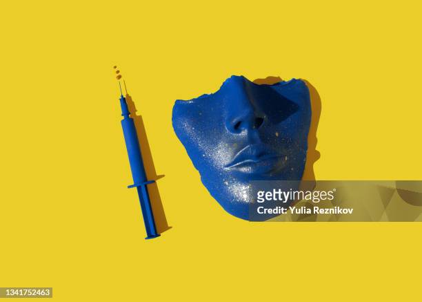 blue colored syringe and face/ mask on the yellow background. - botox fotografías e imágenes de stock