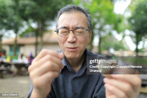 man eating sour biscuit making a funny face - bitter stock pictures, royalty-free photos & images