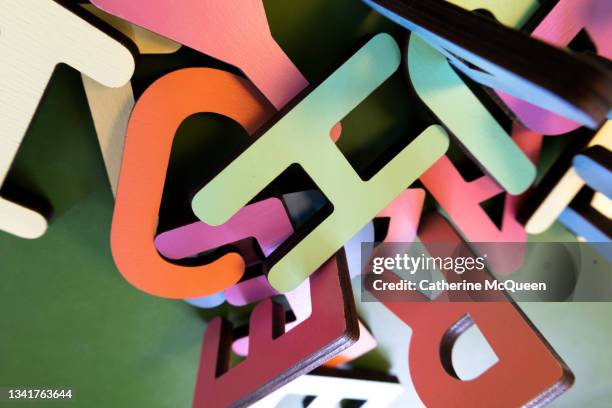 scramble of variously colored wooden alphabet letters - dyslexia stock pictures, royalty-free photos & images