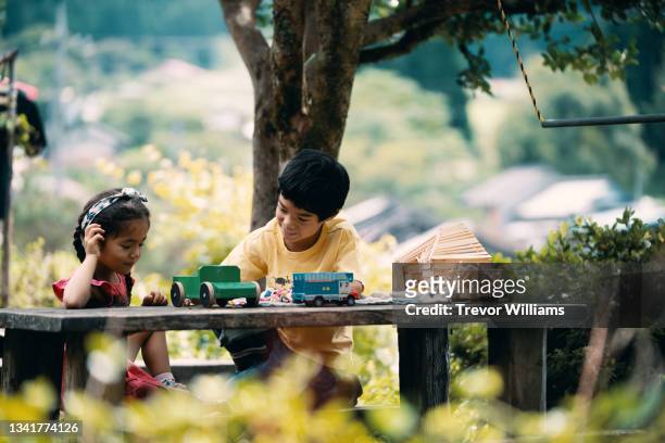 young brother and sister playing together with toys outside - cute japanese boy stock-fotos und bilder
