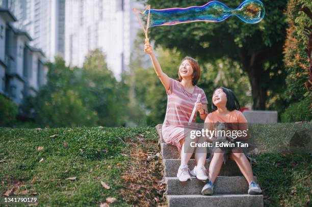 asiatische chinesische mutter tochter, die mit blase im hinterhof ihres hauses mit katze während der freizeit am sonntagmorgen spielt und zeit miteinander verbringt - asian family in park stock-fotos und bilder