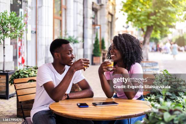 portrait of stylish black couple at summer street cafe. - daten stockfoto's en -beelden