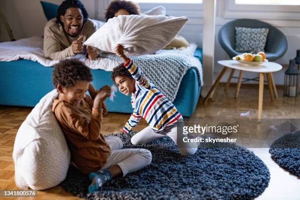 playful african american kids having fun during pillow fight at home. - sibling fight stock pictures, royalty-free photos & images