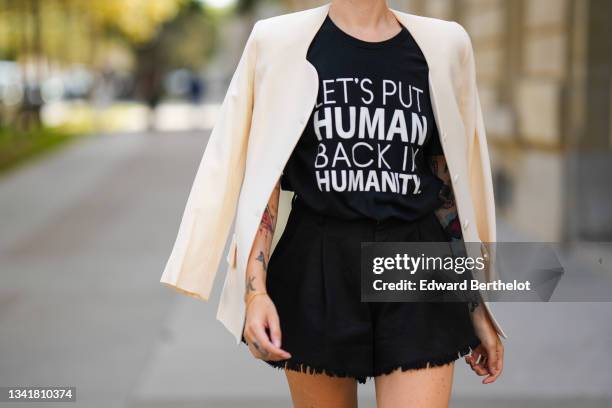 Emy Venturini wears a black with a white slogan t-shirt from Kindom Shop, a white latte vintage blazer jacket, black fringed high waist shorts from...