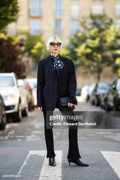 Emy Venturini wears black Dita Eyewear sunglasses, a black with small and large white polka dots scarf, a black oversized vintage blazer jacket from...