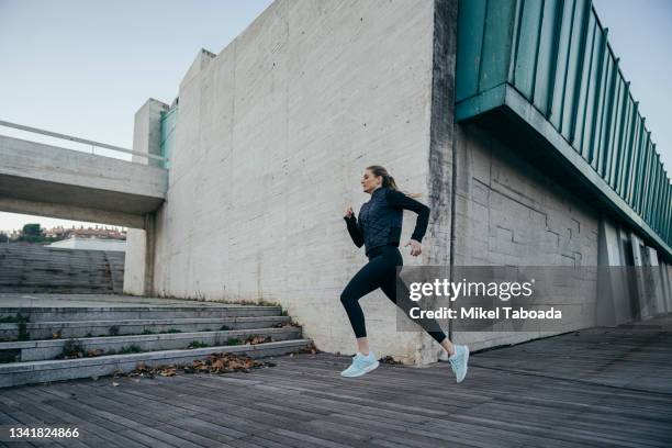 woman running against modern building - jogging city stock-fotos und bilder