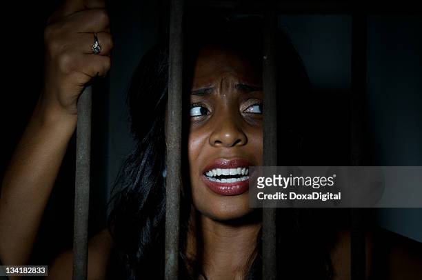 young woman behind bars - women in prison stock pictures, royalty-free photos & images