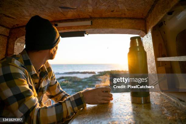 over shoulder view man with travel mug looking out back of camper van - coffee car design stock pictures, royalty-free photos & images